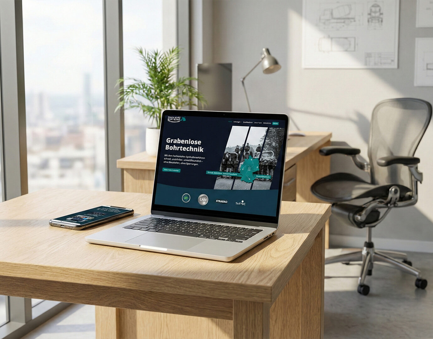 Moderne Businesswebseite eines Bohrtechnik-Unternehmens auf einem Laptop dargestellt, ergänzt durch Smartphone-Ansicht, auf einem Schreibtisch in einem hellen Büro mit Blick aus dem Fenster.