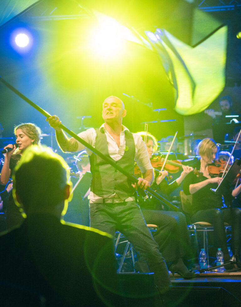 Saengerin mit Orchester bei einem Konzert in gruenem Buehnenlicht