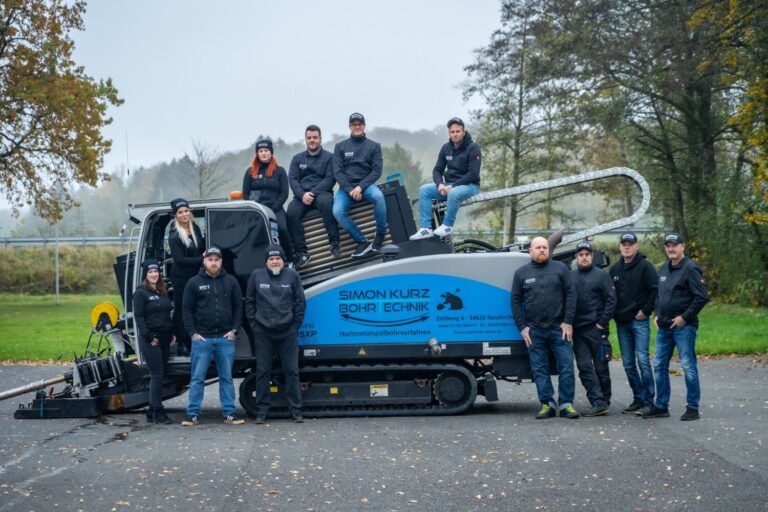 Team eines Bohrtechnik-Betriebs vor einer Bohranlage